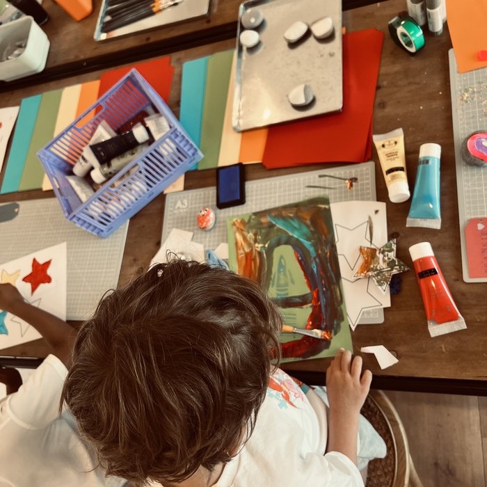 A child painting at the craft table, seen from above