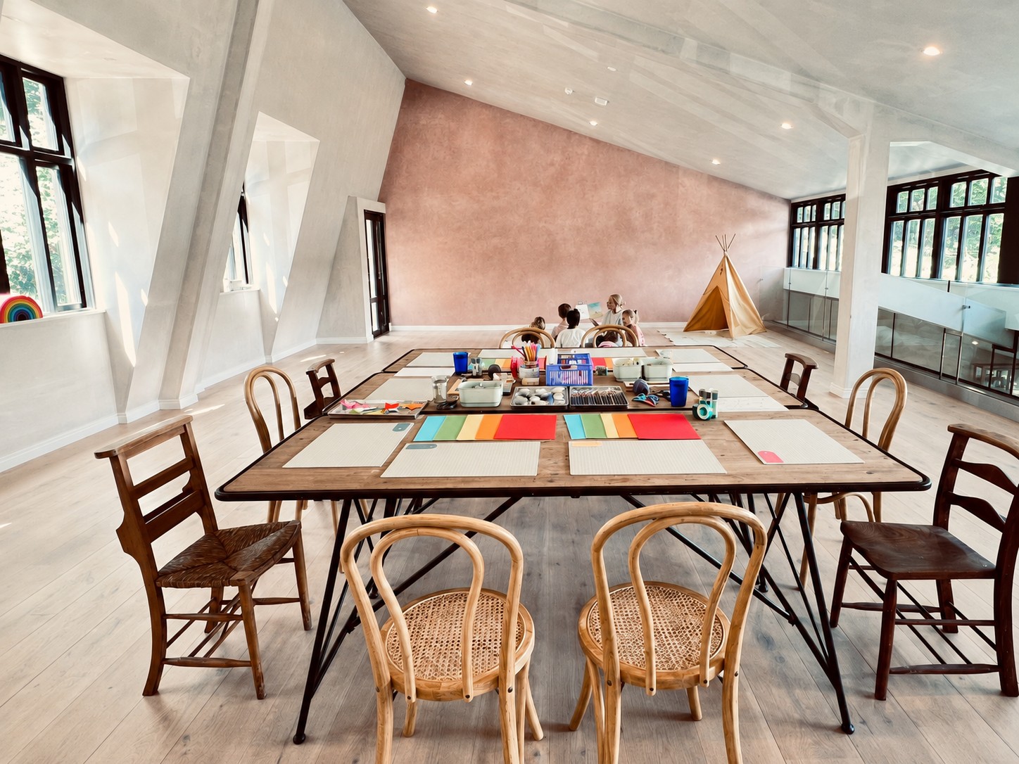 The Little Circle studio room set up before a session, with a long table, coloured paper and a teepee in the corner